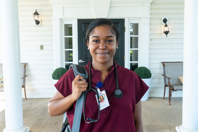 Brittany, RN Hospice Nurse Case Manager, standing in front of the Hospice of the Piedmont building.