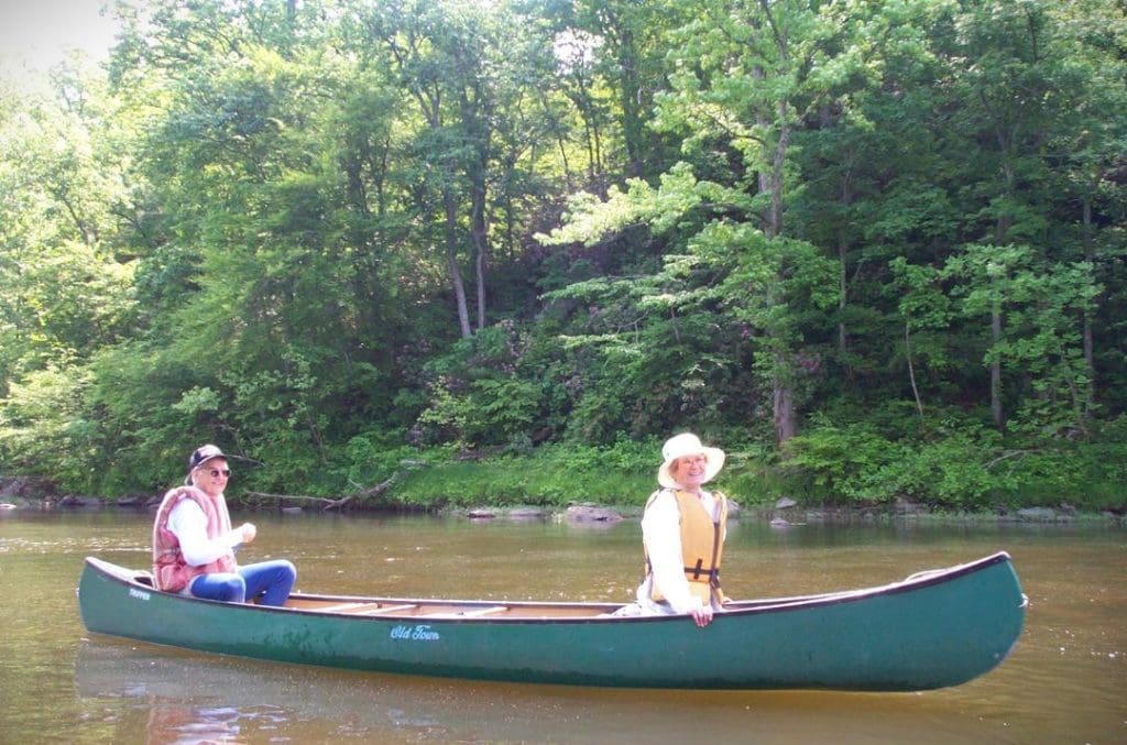 An older couple canoes down a river