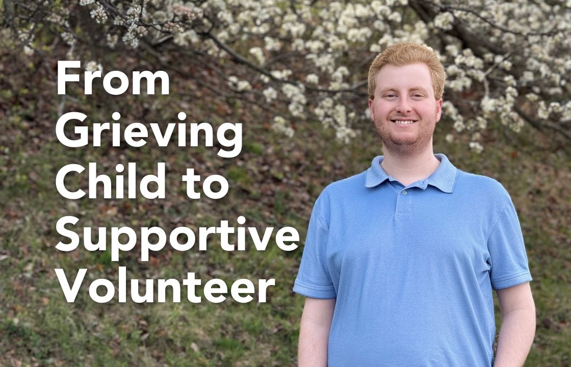 Volunteer Bradley Keats wears a light blue polo shirt and stands in front of a spring outdoor background