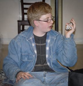 As a grieving child, young Bradley Keats holds a pocket watch and wears a denim jacket.