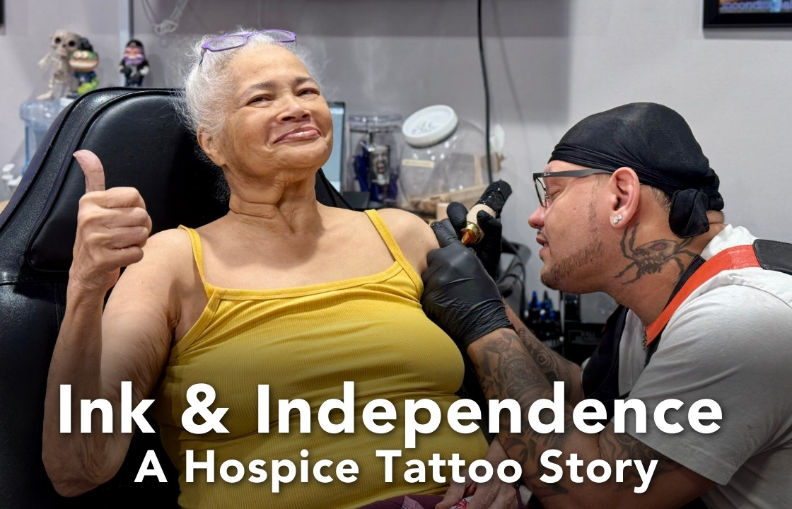 A hospice patient in a yellow tank top flashes a smile and thumbs up, while a tattoo artist with a skull and spider neck tattoo gives her a tattoo on her arm.