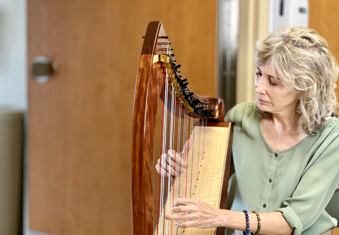 Woman playing harp during therapeutic music session for hospice patient care