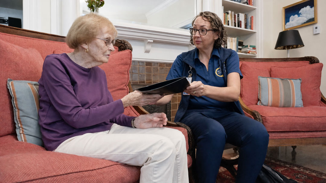 Hospice nurse reviewing information with a patient during an in-home visit.
