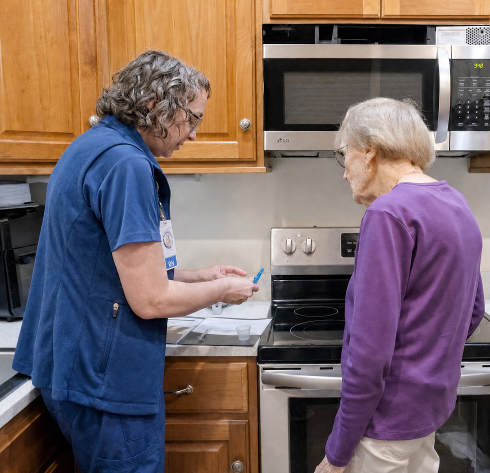 Hospice nurse providing in-home care and medication support to a patient in a residential kitchen, helping manage health and daily care needs.